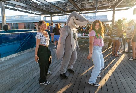 Two EOP students dancing with Elbee the shark mascot.