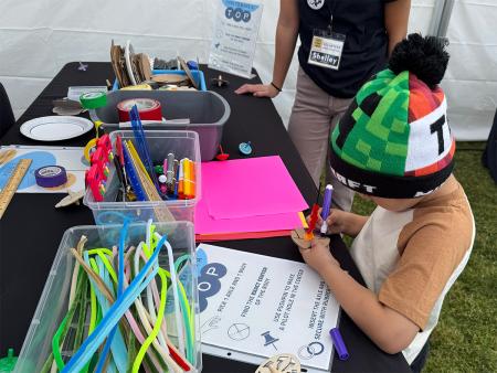 kid using markers, cardboard, and pipe cleaners to construct a device