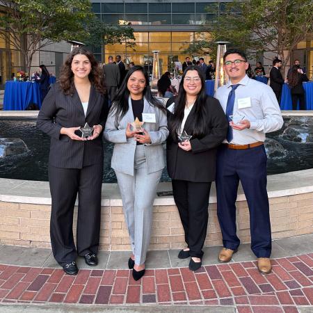 Four people holding star-shaped awards at an outdoor event