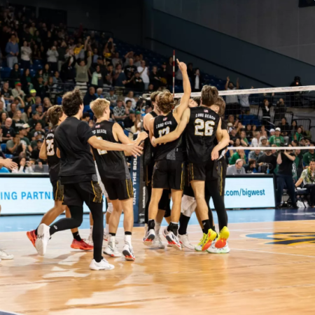 A volleyball team celebrates together on the court after a match