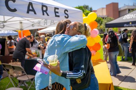 Two people hugging in front of the CARES booth.