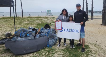 3 people holding a Caltrol Sign at the Advisory Board Beach Clean Up Event