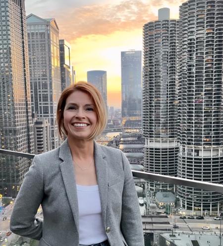 HDEV Dept Chair Kim Kelly smiling in front of a city skyline