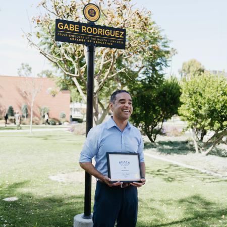 Gabe Rodriguez stands in front of a sign bearing his name