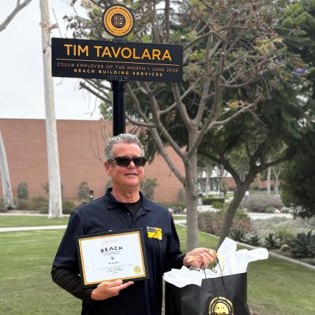 Tim Tavolara standing in front of Employee of the Month sign