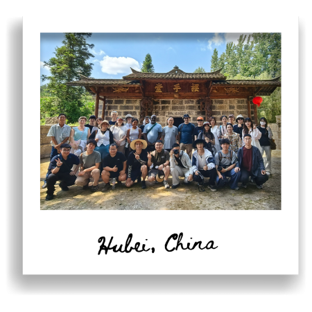 A group of people pose together in front of a traditional wooden building