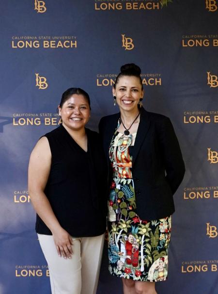 Holli and Nanci standing in front of a blue backdrop