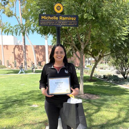 Michelle Ramirez '13 stands in front of her Employee of the Month sign