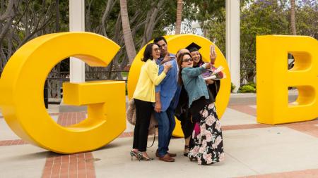 Family and graduate at the Go Beach sign