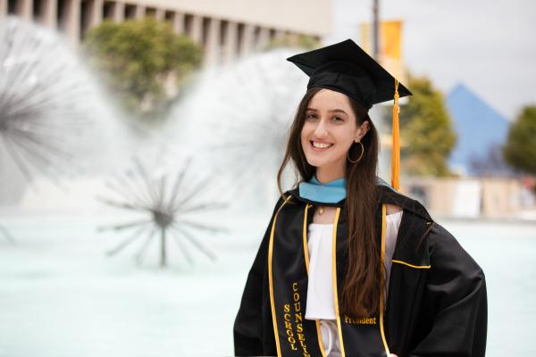 Graduate in front of Brotman hall fountain Scrolling pictures of a graduate