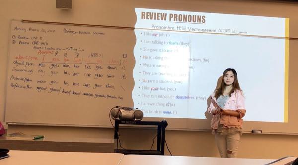 Yutong teaching Young woman stands in front of a whiteboard, teaching pronouns in various languages
