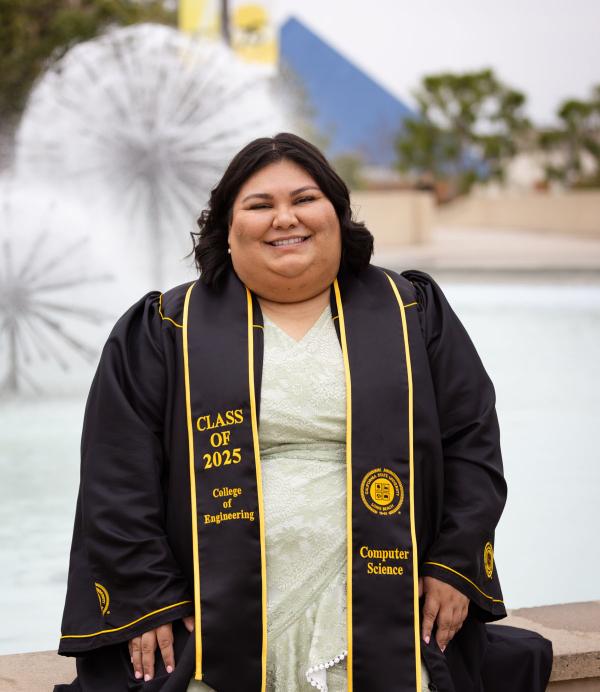 Graduate sitting in front of the water fountain by Brotman Hall