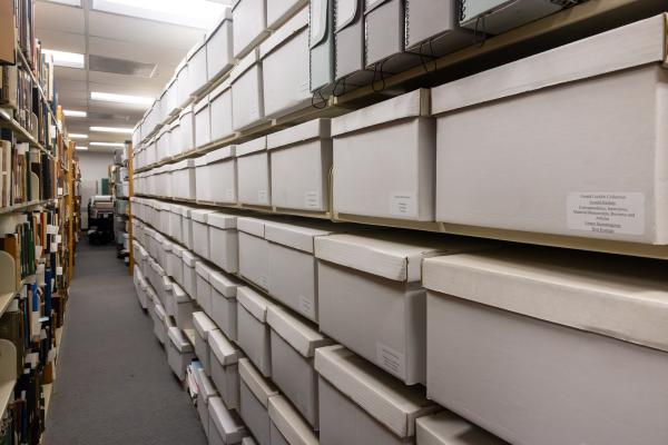 Rows of labeled archival storage boxes line shelves in the CSULB archives.