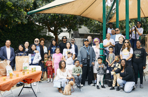 Crowd of 30 community members in a local Long Beach park posing for a photo in front of a playset