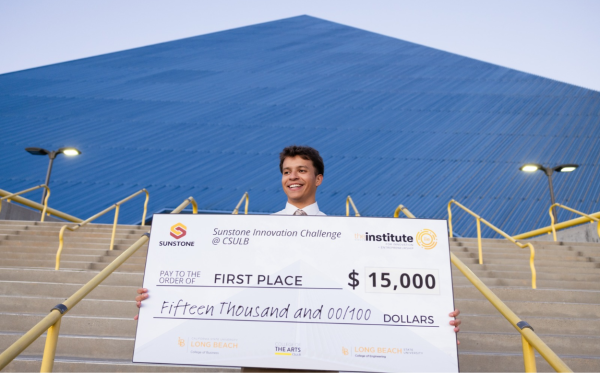 man holding jumbo check in front of blue pyramid