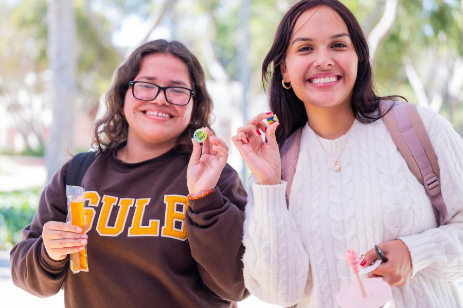 Beach XP activity hour Two students smile at camera while holding decorative pins