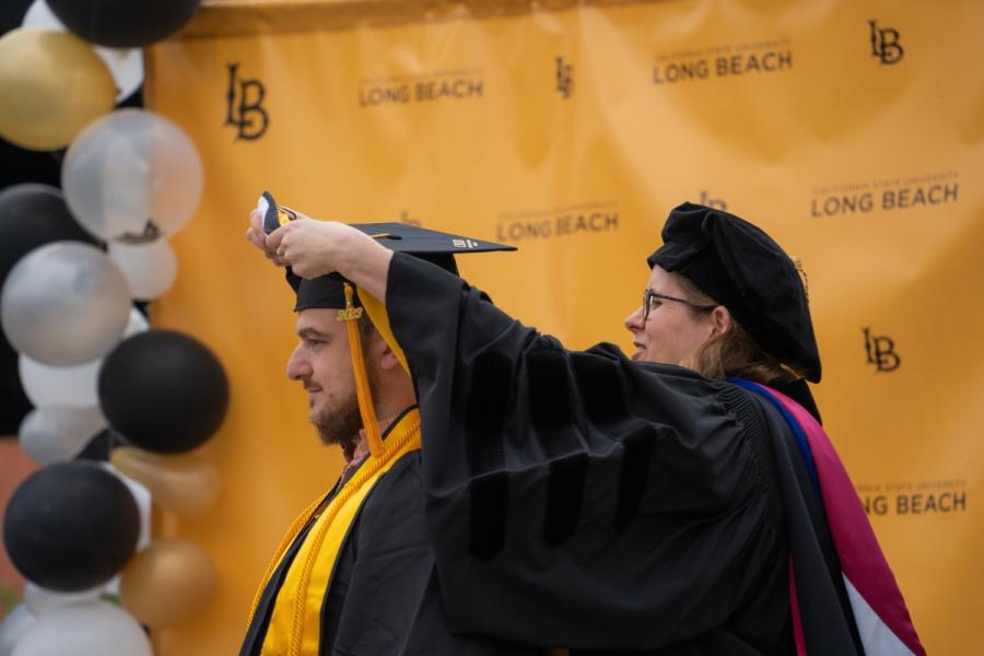 Dr. Hall places grad cap on student Dr. Hall places grad cap on student