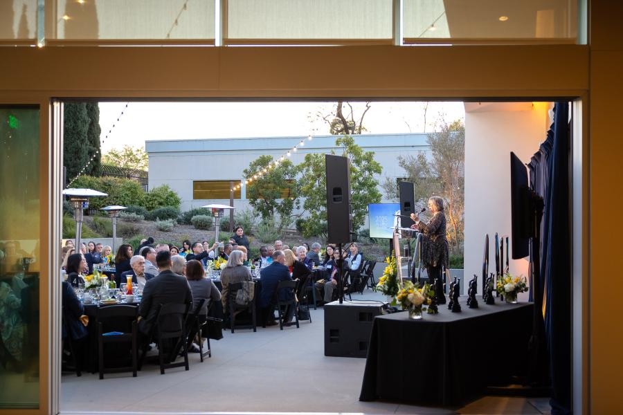 The audience at the 2025 Distinguished Alumni Awards listens as campus President Jane Close Conoley speaks at the podium.