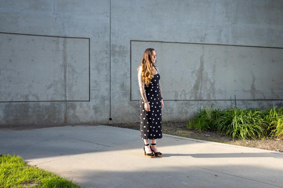 Taryn Williams stands against gray wall and sidewalk