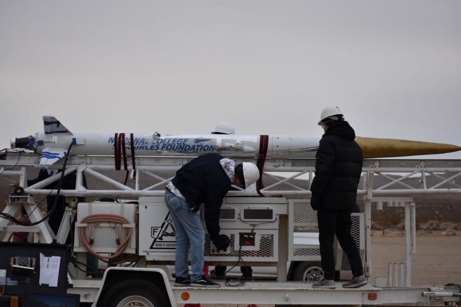 Students examining a rocket on the day of a launch