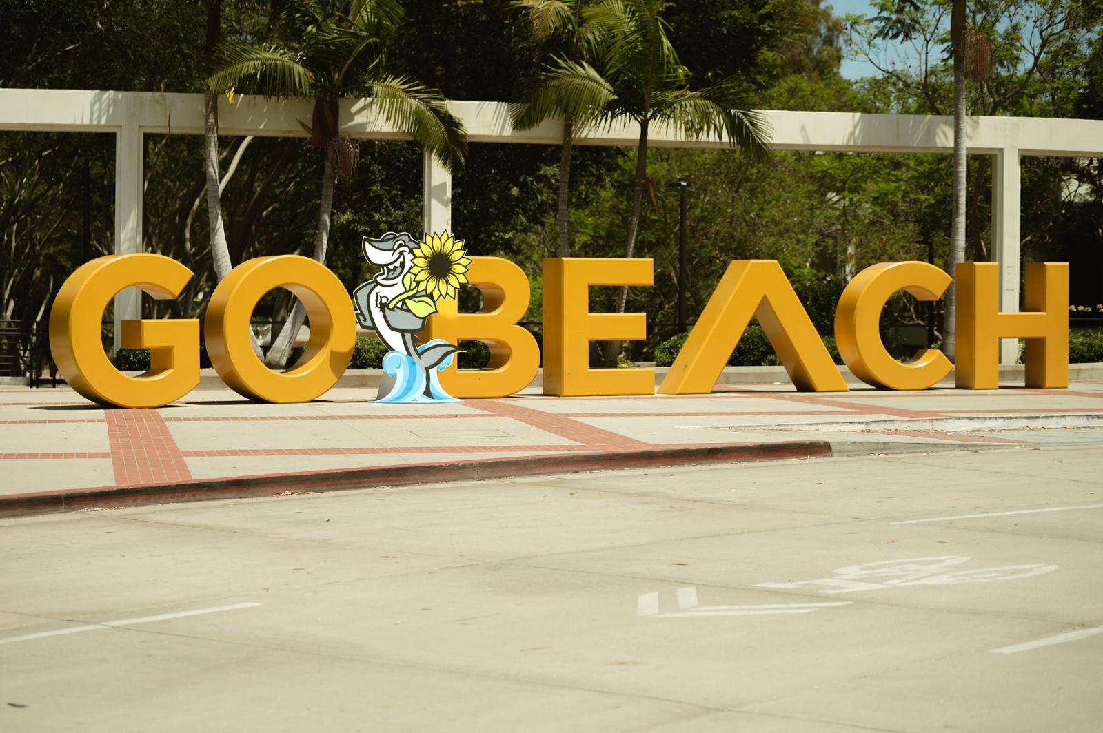 Elbee with a sunflower in front of Go Beach sign Elbee with a sunflower in front of Go Beach sign