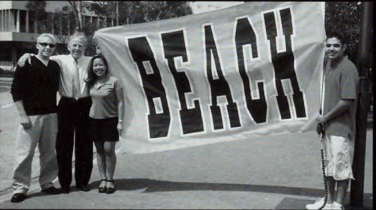 Four people, including Robert Garcia, stand by a large sign that reads "BEACH." Four people stand by a large sign that reads "BEACH."