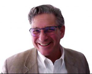 Dr. Marcus Dr. Marcus is a white man with grey hair and glasses. He is wearing a white shirt and khaki blazer