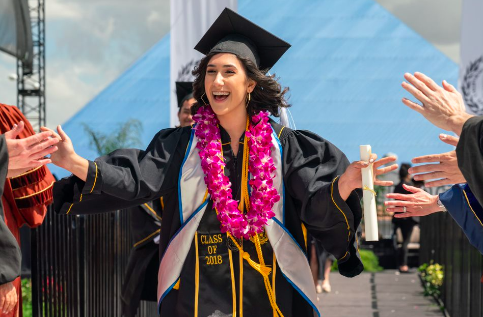 Ling grad pic Graduating Ling student runs through aisle high fiving people on the sidelines and smiling
