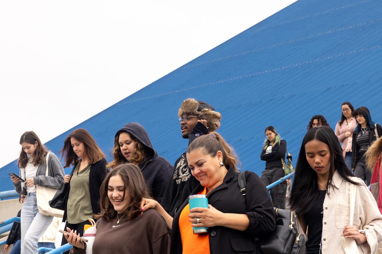 A group walks down blue stairs beside the Walter Pyramid at CSULB.