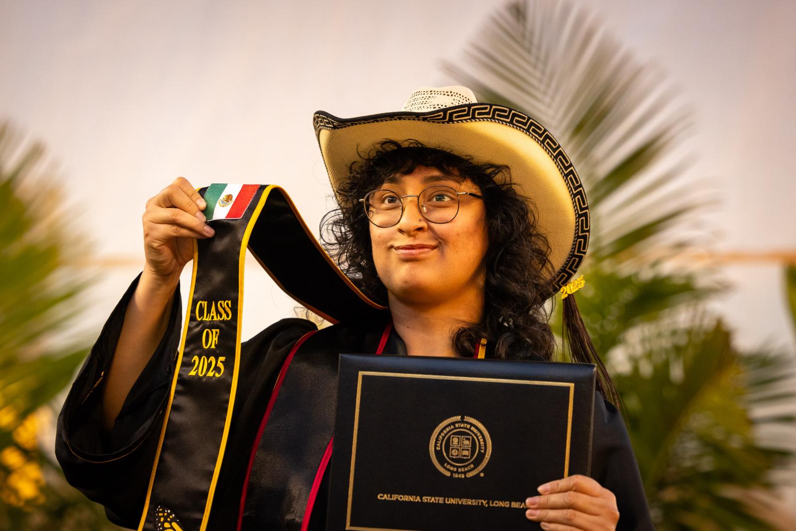 Graduate holds up flag of Mexico on stole at Commencement