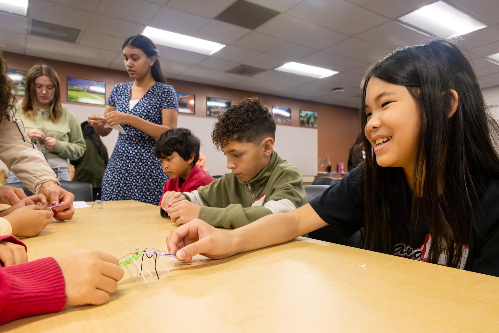 Two Handy Elementary students play with their robotic bugs as CSULB student teachers help others