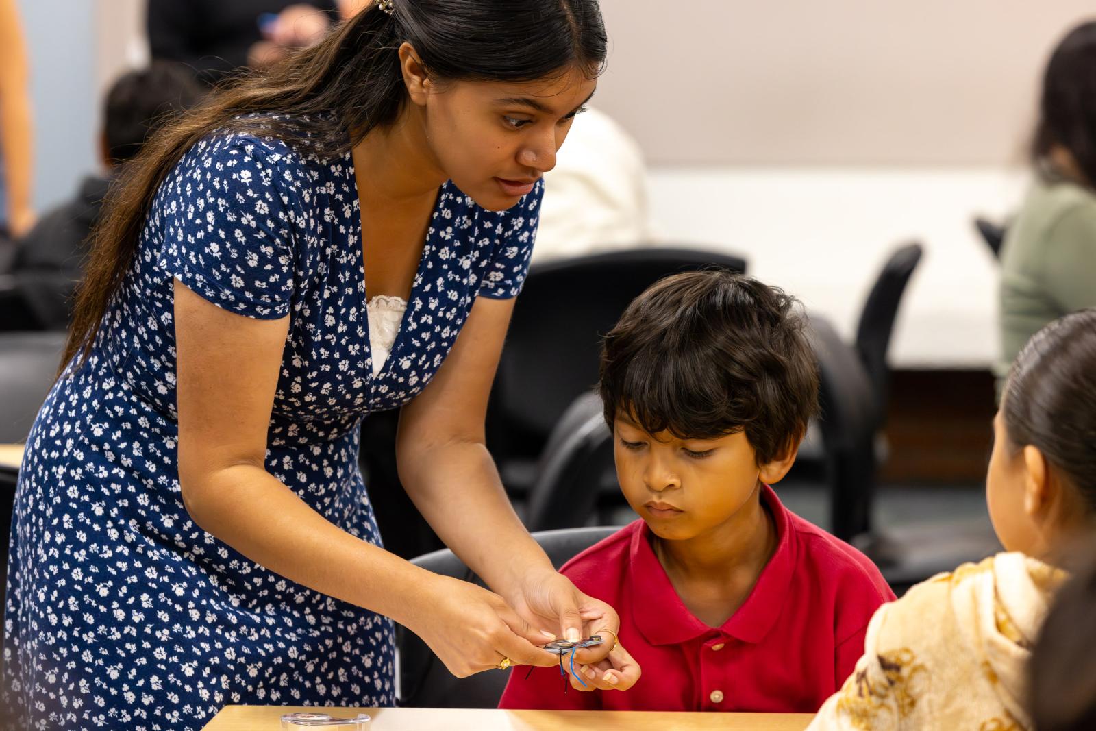A CSULB student teacher guides a Handy Elementary student on building a robotic bug