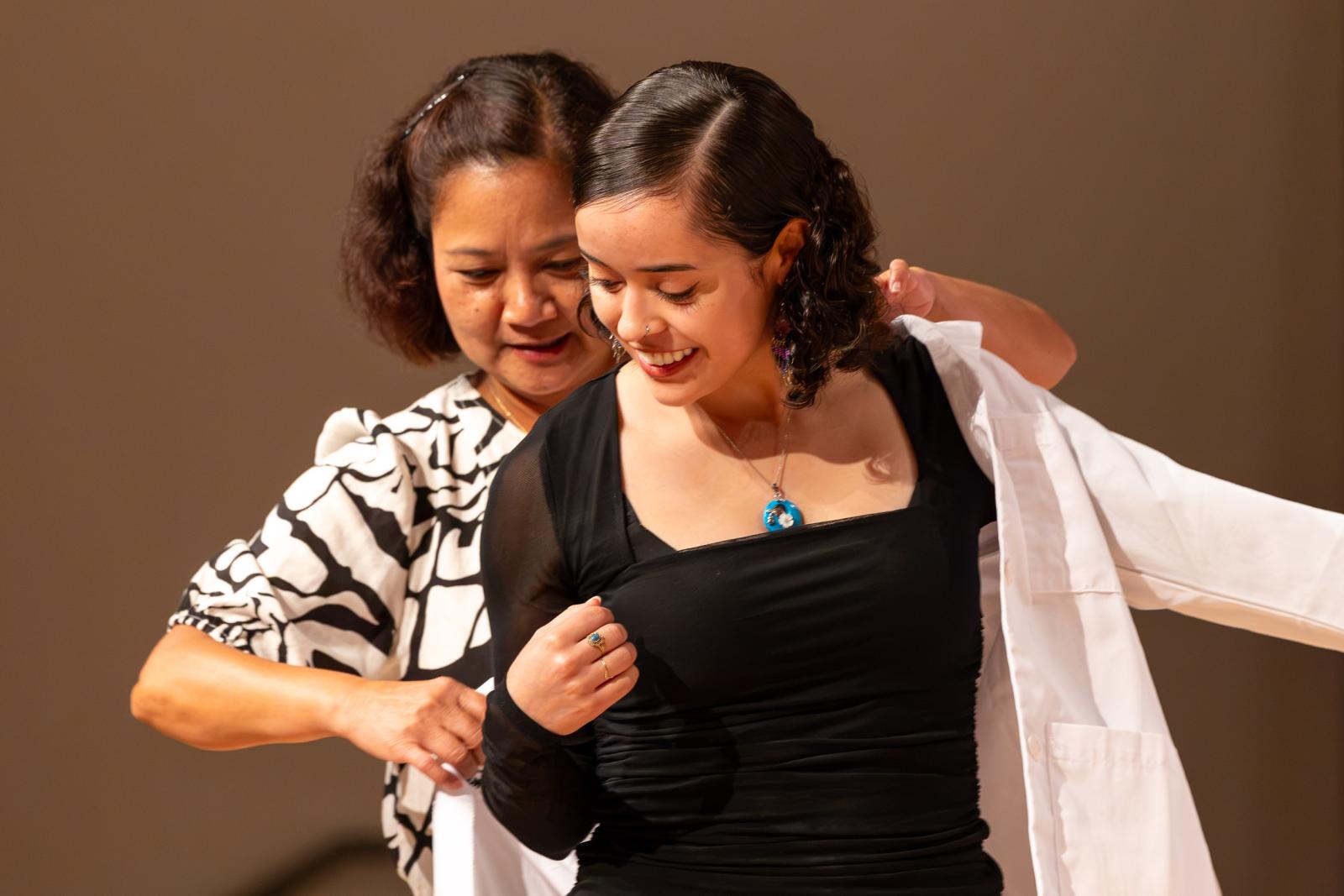 A faculty member helps a student put on a lab coat at the 2026 White Coat Ceremony