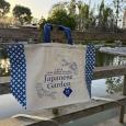 Blue Tote Bag with EBM Japanese Garden 45th Anniversary logo, hanging on the Koi Deck in front of the pond