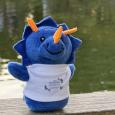 Blue Triceratops Stuffed Animal with a white EBM Japanese Garden 45th Anniversary t-shirt, sitting on Koi Deck infront of the pond
