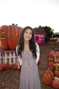 person smiling in front of pumpkins