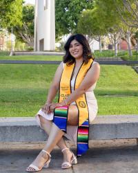 CDFS alumni wearing a graduation banner and posing on campus